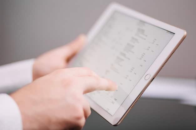 A close-up of a doctor's hands using a tablet, displaying a complex data dashboard with real-time patient information.