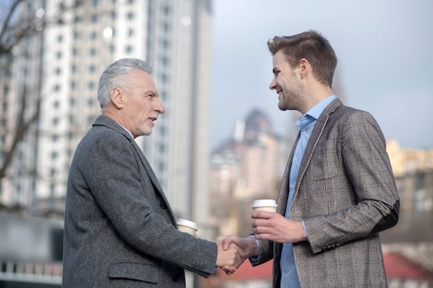 Two business professionals, possibly a father and son, shaking hands over a deal, symbolizing the transfer of power and responsibility.